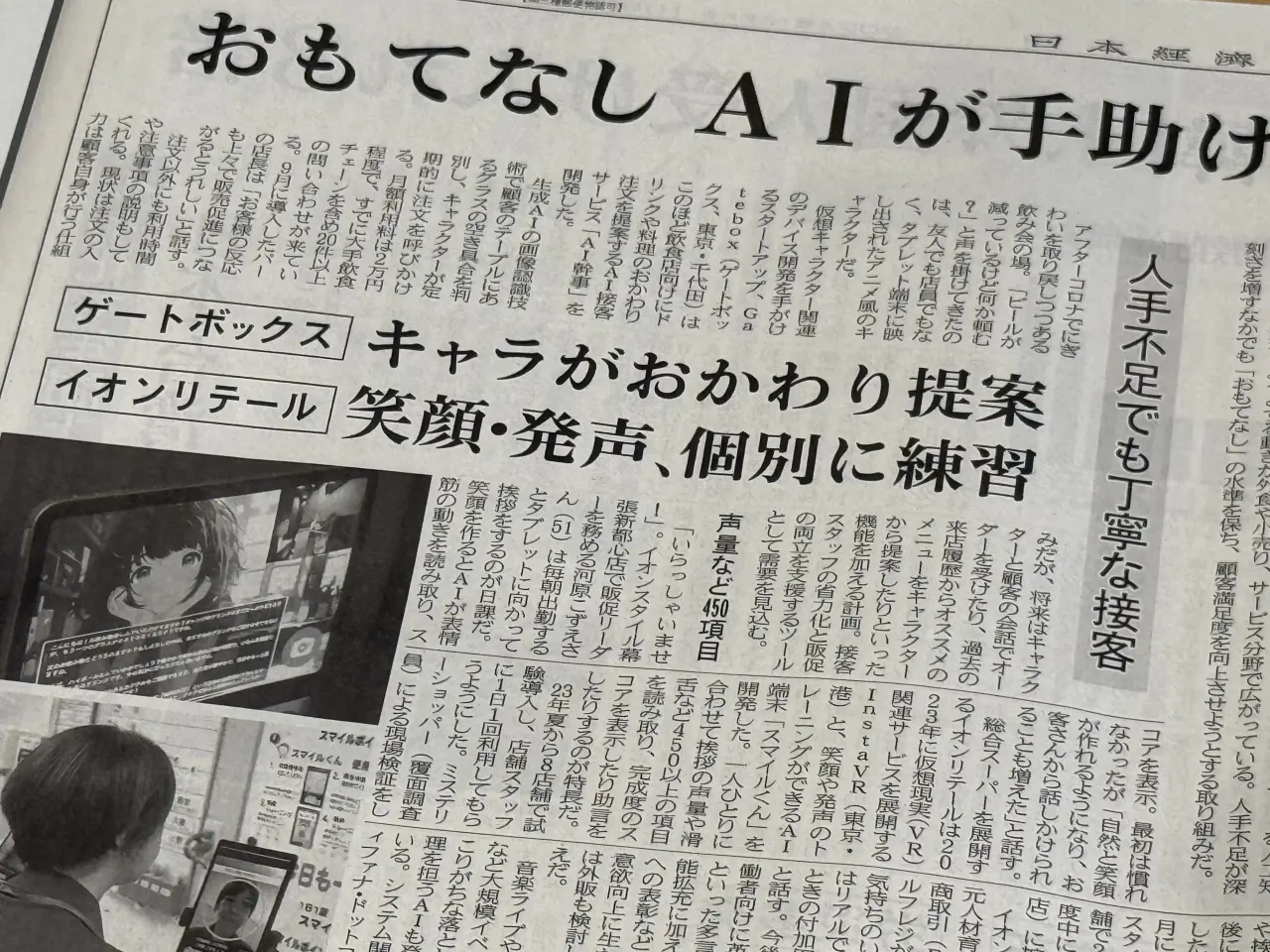 日本経済新聞に掲載されたAI幹事の紙面。「おもてなし AIが手助け」「キャラがおかわり提案」の見出しで、タブレットに映るAIキャラクターの写真が添えられている